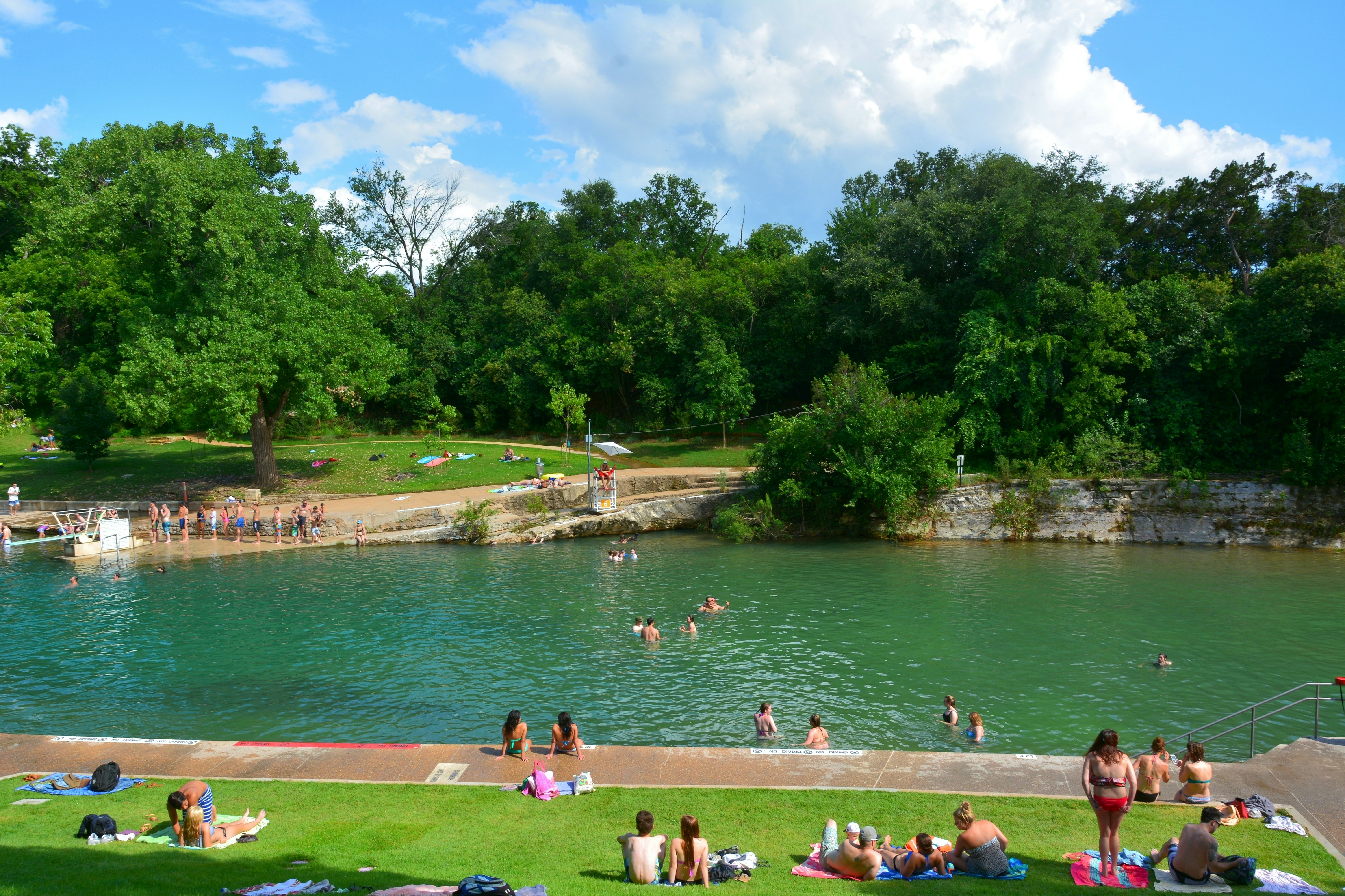 Outdoor springs. People line up to use a diving board; others swim or lounge by the side
