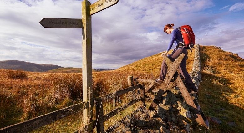 A woman crossing a stile on the Pennine Way, English Countryside walk.UK; Shutterstock ID 275558420; your: Brian Healy; gl: 65050; netsuite: Lonely Planet Online Editorial; full: Best hikes in the UK