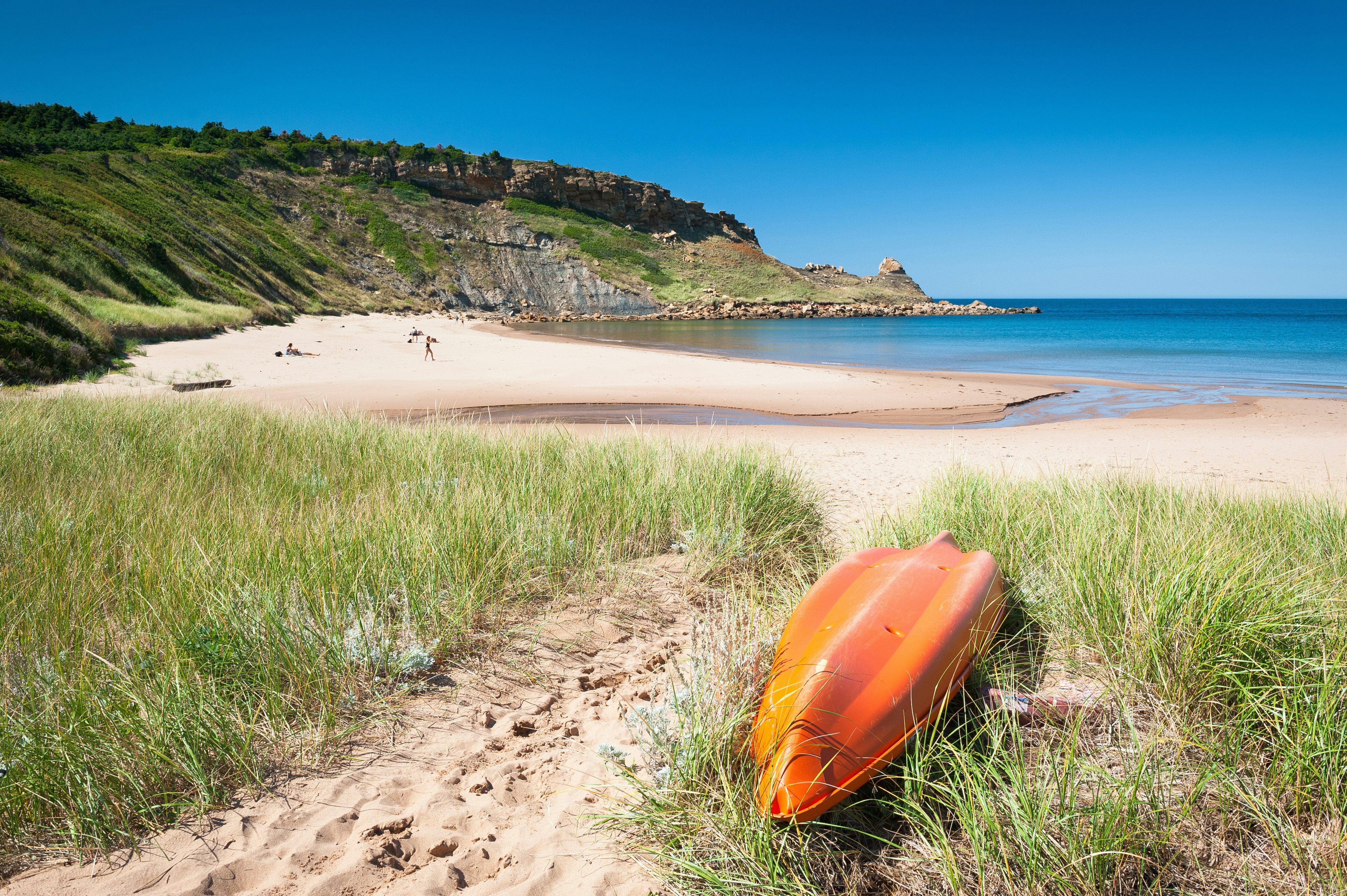 A kayak sits in the grass next to Chimney Corner Beach, Cape Breton, Nova Scotia