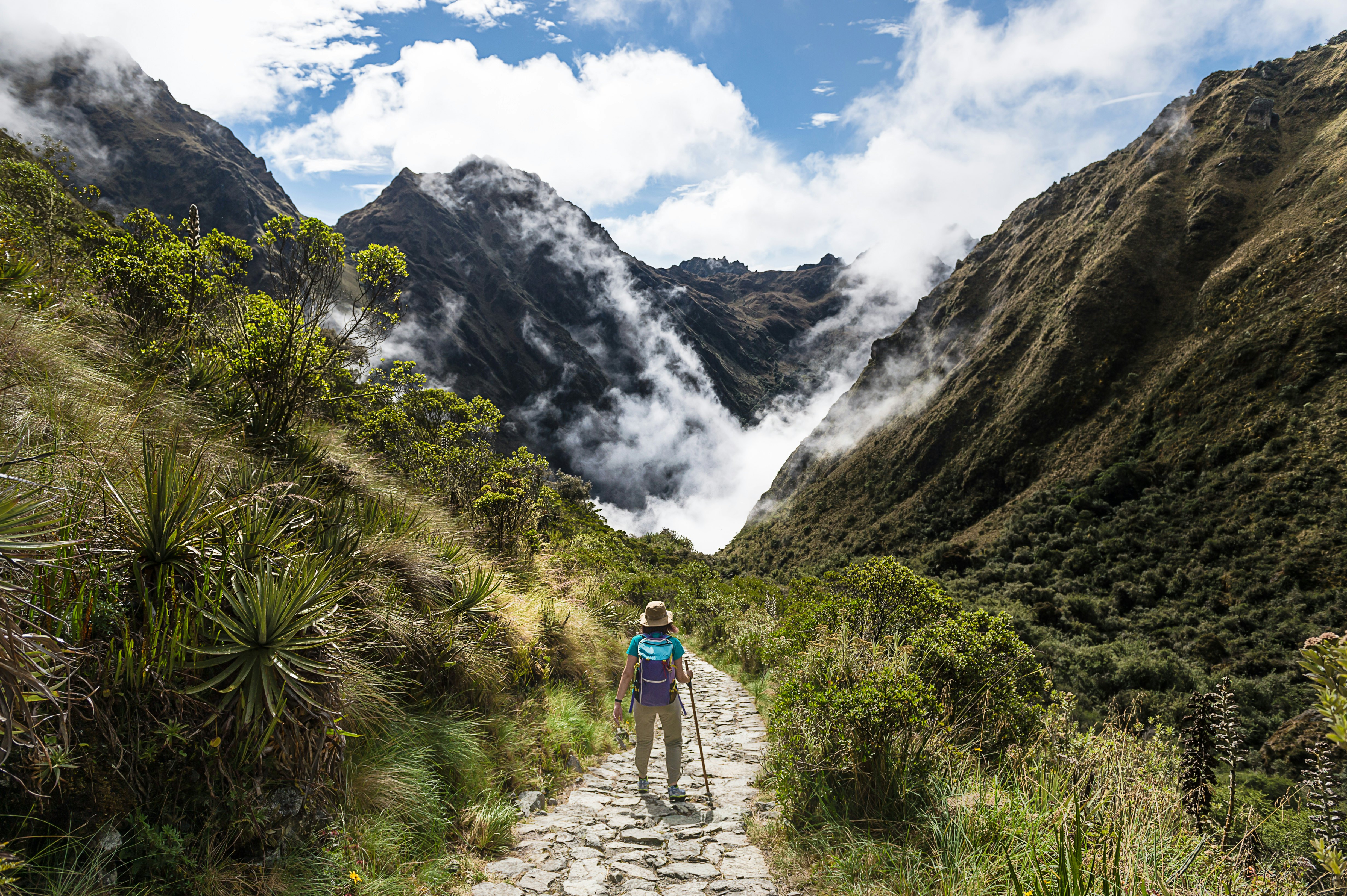 Female trekker walking through a misty valley on the Inca Trail, Peru.