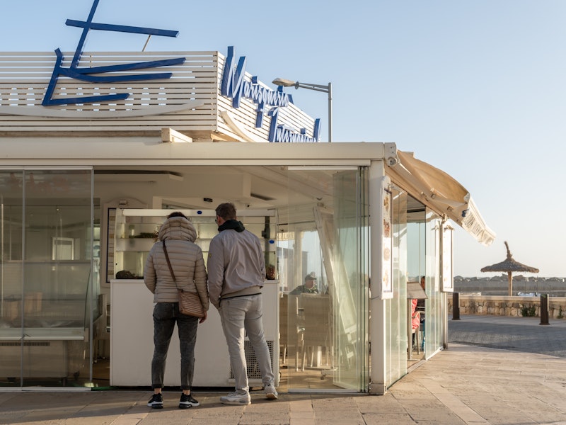 General view of a seafood restaurant in Playa de Palma de Mallorca at sunset, with customers on the premises. Island of Mallorca, Spain
