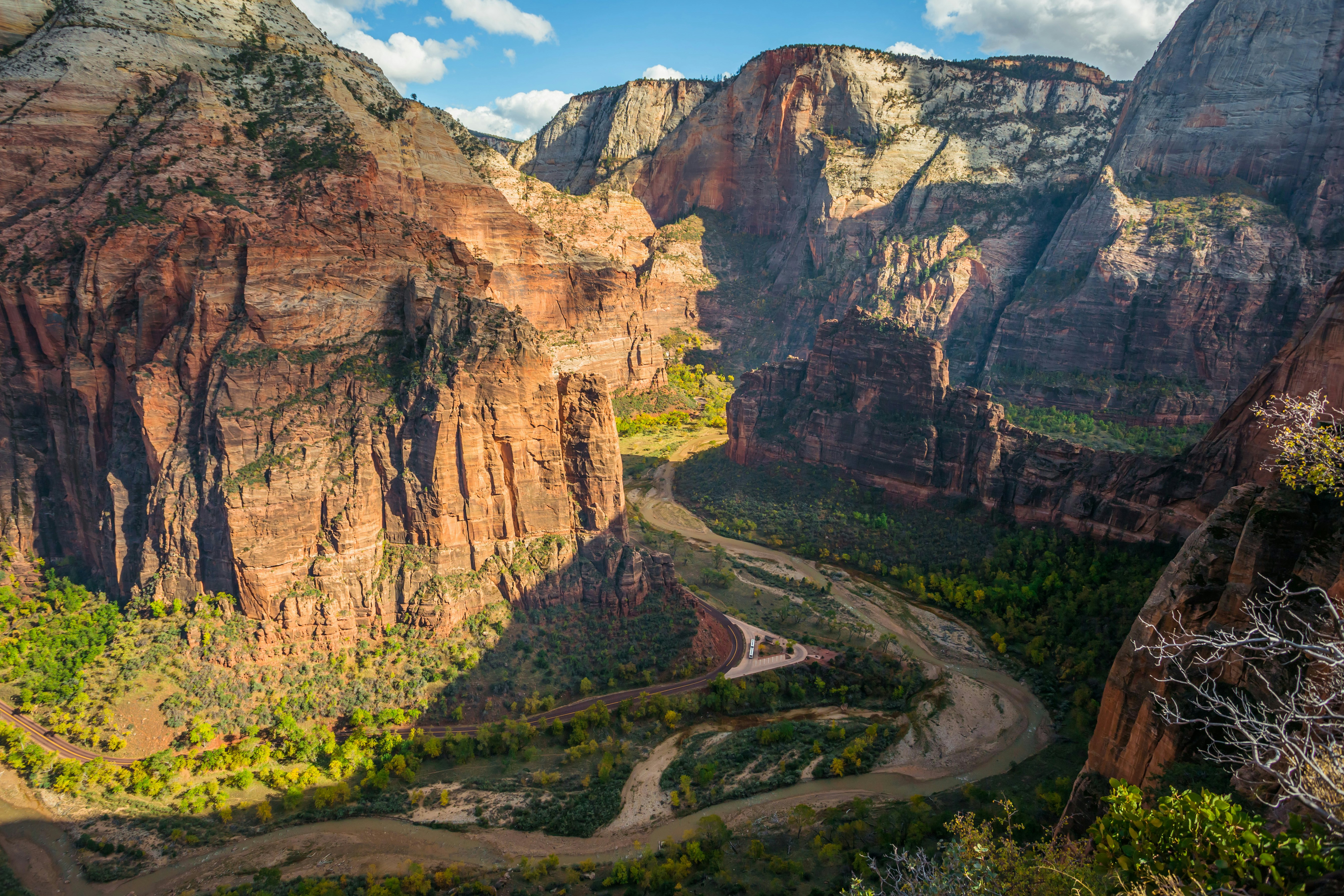 Colorful, rocky valley with river and wavy roads, green forest and blue sky with clouds in Zion National Park.
