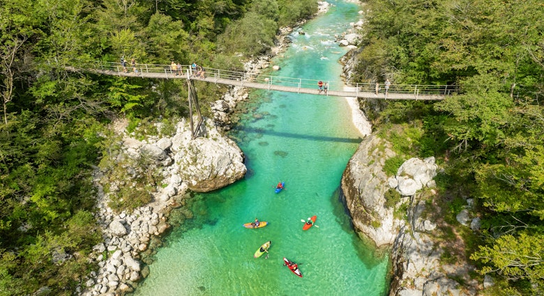 A suspension bridge spans the emerald waters of the Soca River in Slovenia, aerial view. This spot is a favored destination for kayaking and trekking in Slovenia., License Type: media, Download Time: 2025-02-24T21:44:35.000Z, User: rhylton_redventures, Editorial: false, purchase_order: 56530 - Guidebooks, job: Lonely Planet WIP, client: Lonely Planet WIP, other: Rhianydd Hylton