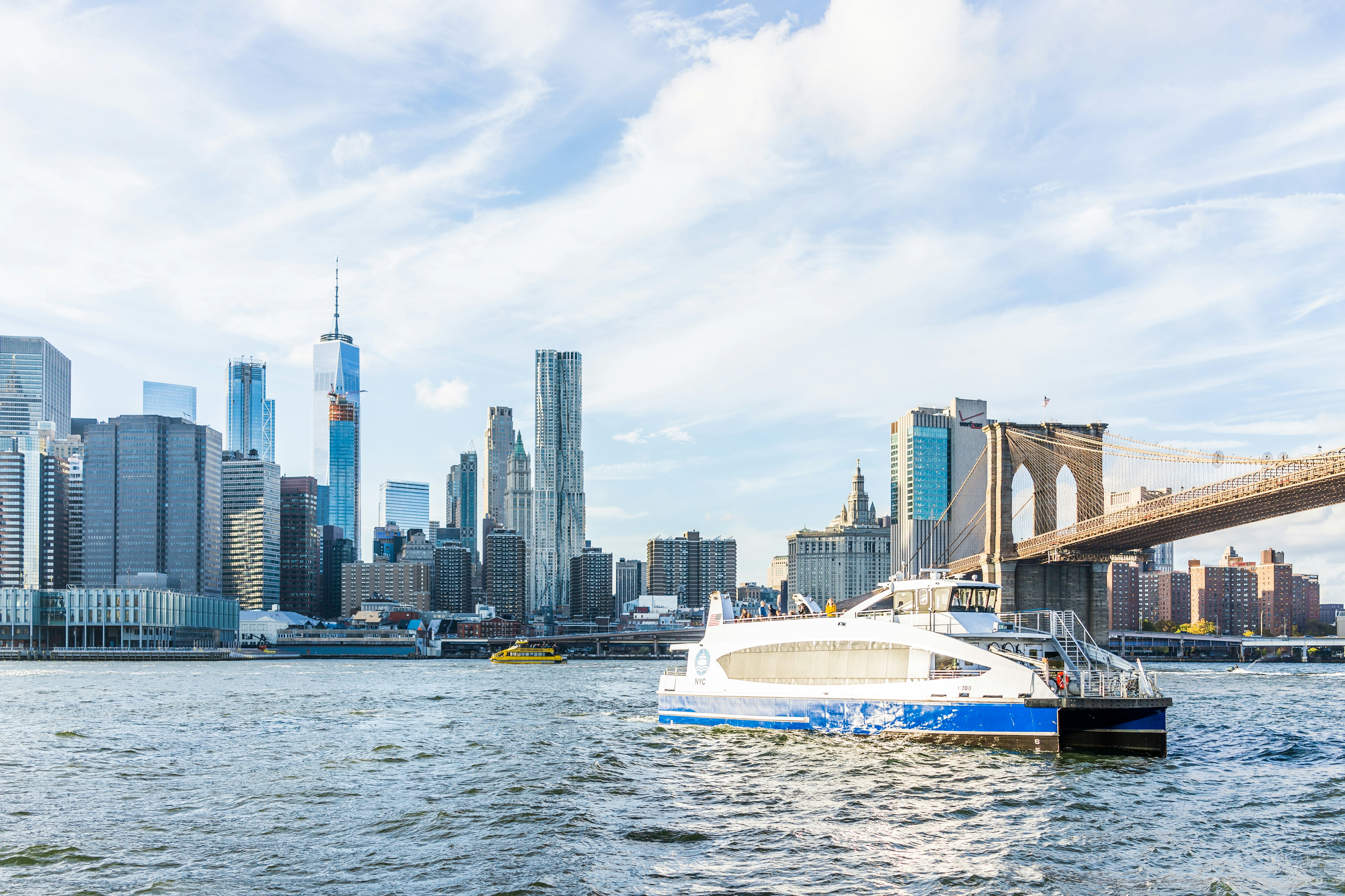 A ferry in the East river with the New York City skyline beyond.